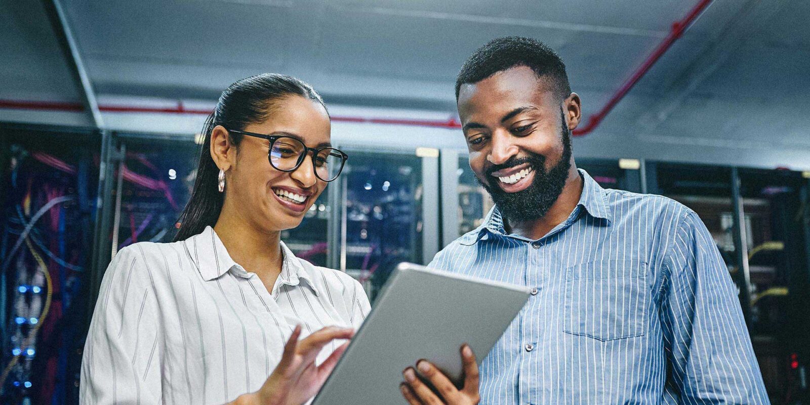 Man and woman looking at tablet in server room of technology department