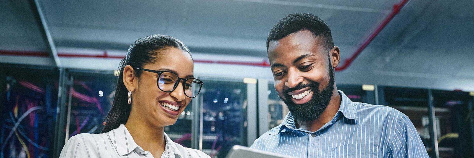 Man and woman looking at tablet in server room of technology department