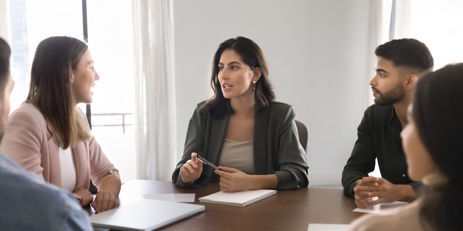 Woman leading a discussion with colleagues around a conference table